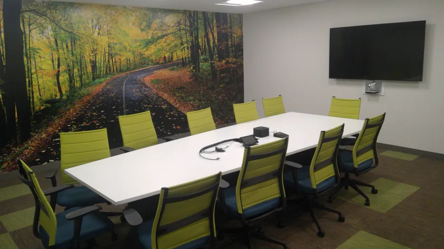 Finished conference room with green chairs and a forest mural
